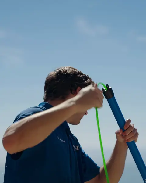 Titan crew member preparing a water-fed pole with the ocean behind him